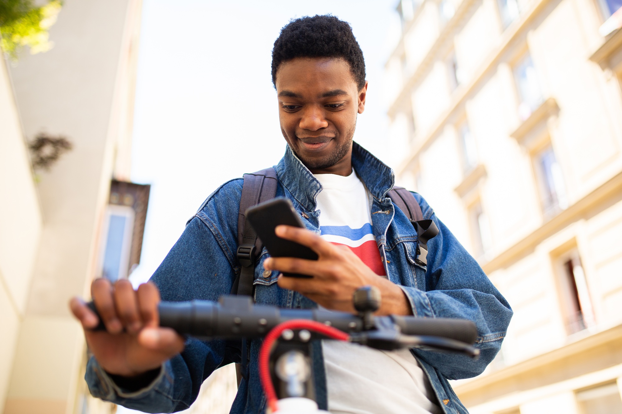 African American man with cellphone and electric scooter